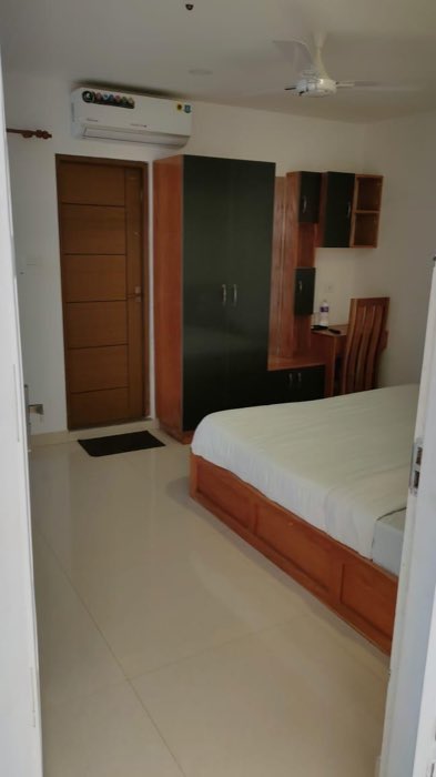 A deluxe room at Vanyora with a double bed, tall wardrobe, writing desk and wall-mounted air conditioner.